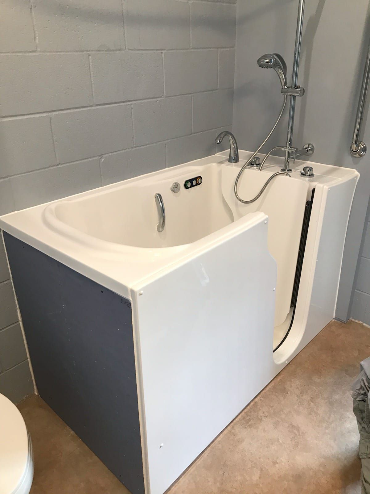 A walk in tub in a bathroom next to a toilet.