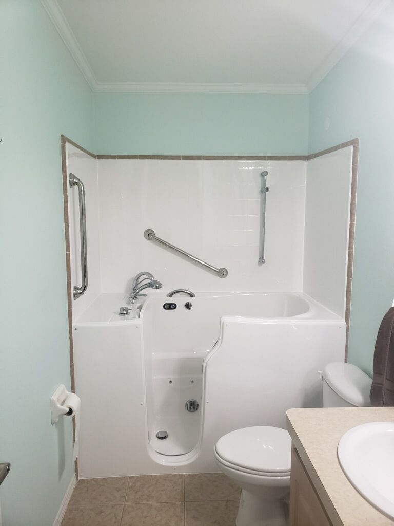 A bathroom with a walk in tub , toilet and sink.