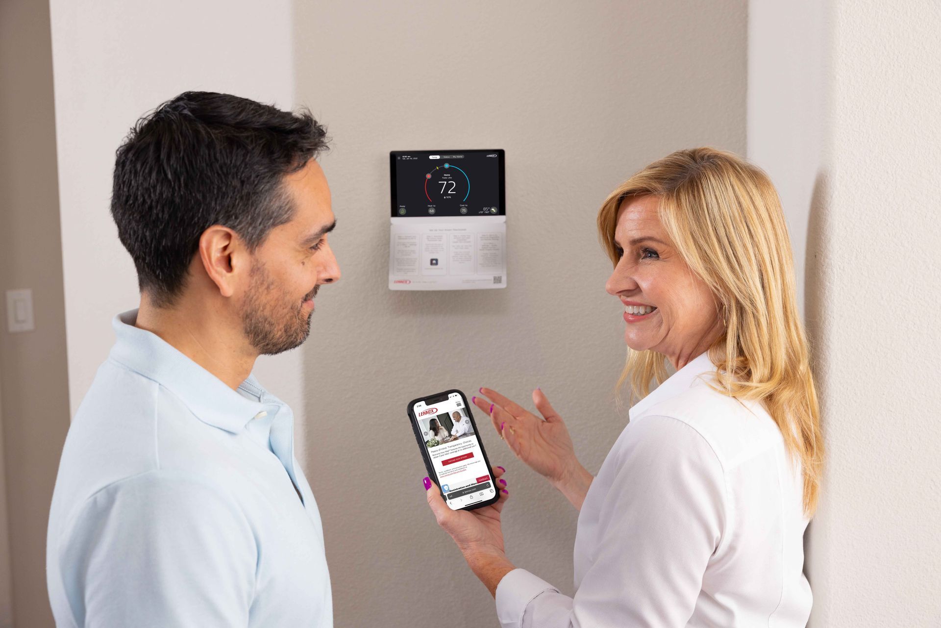 Un homme et une femme se tiennent l'un à côté de l'autre devant un thermostat.