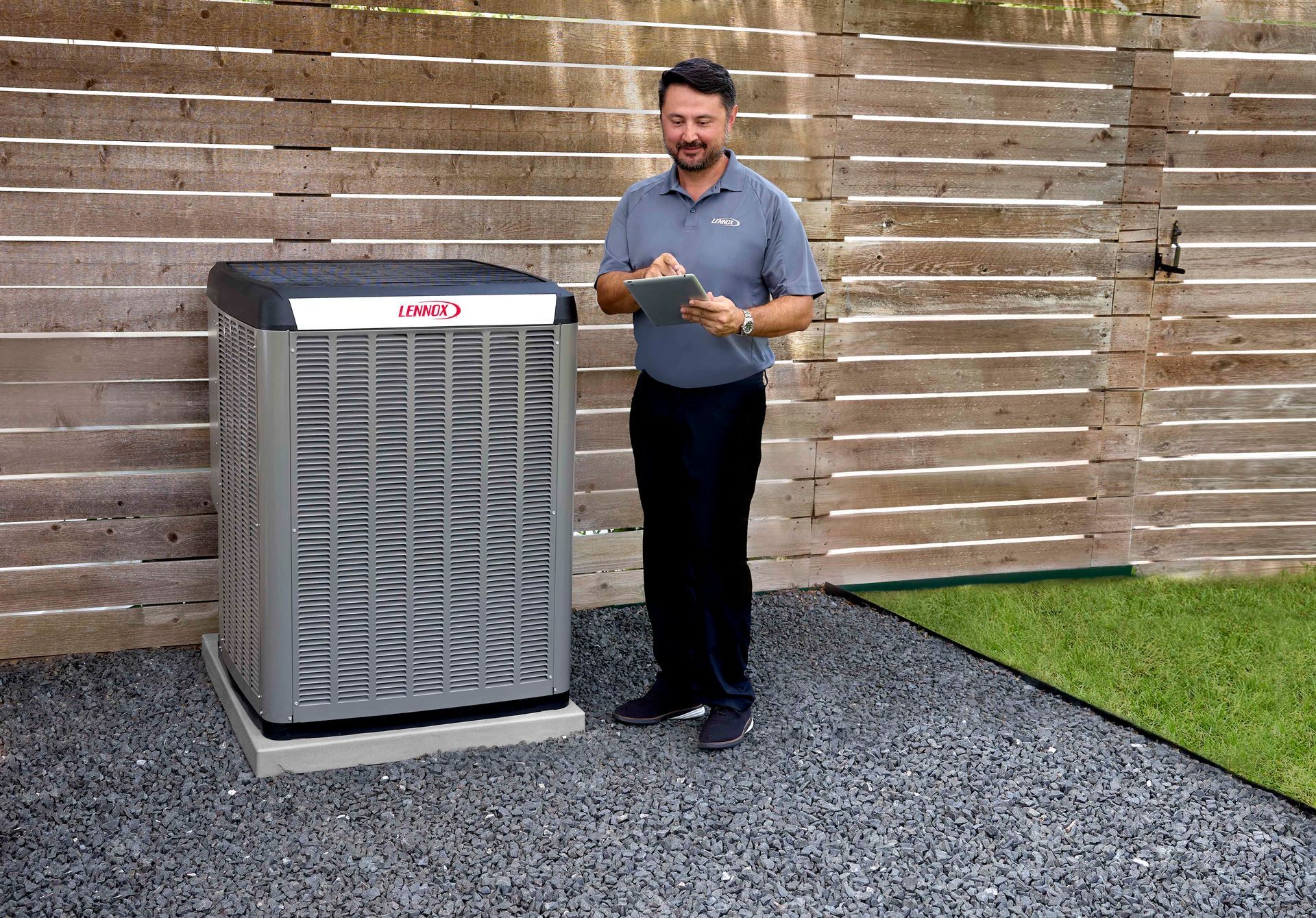 Un homme se tient à côté d'un climatiseur et regarde une tablette.
