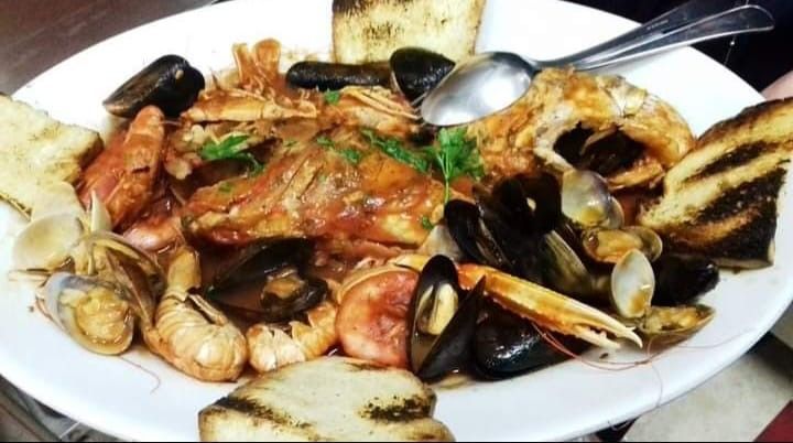 Un piatto di frutti di mare con pane e un cucchiaio su un tavolo