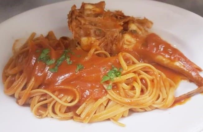 Un piatto bianco condito con spaghetti e salsa