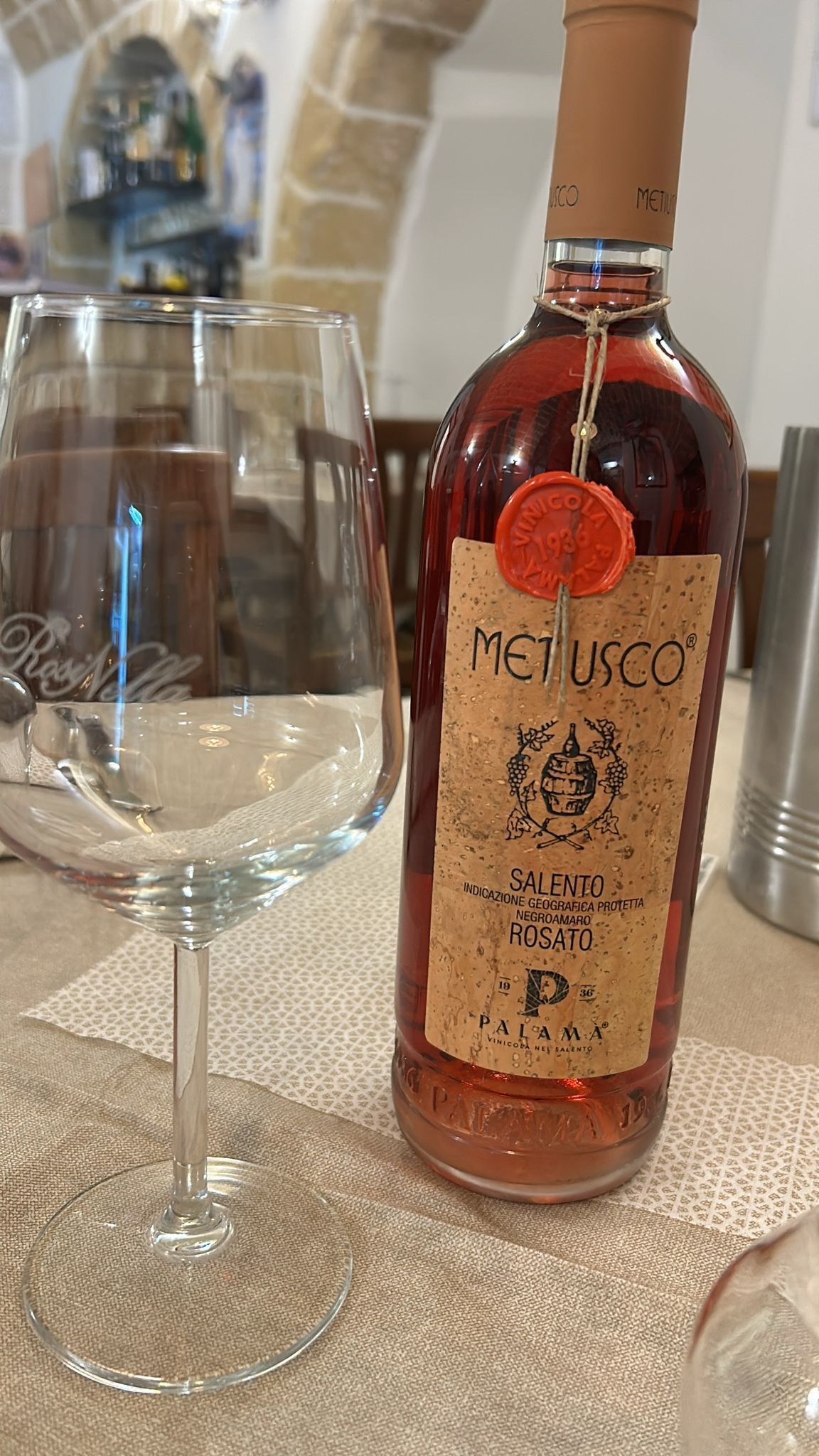 Una bottiglia di vino e un bicchiere di vino sono su un tavolo.