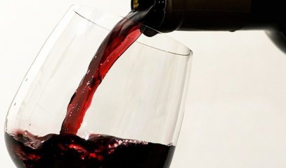 Una bottiglia di vino rosso viene versata in un bicchiere.
