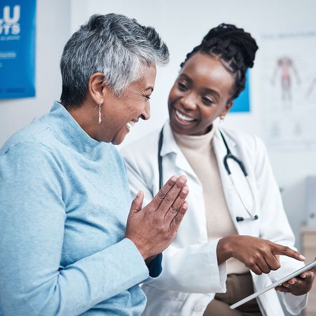 A doctor is talking to a patient who is looking at a tablet.