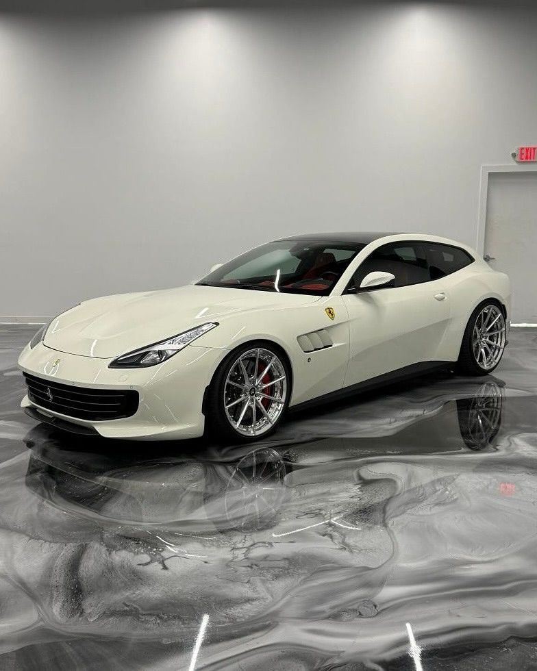 White Ferrari GTC4Lusso in a showroom with a reflective floor.