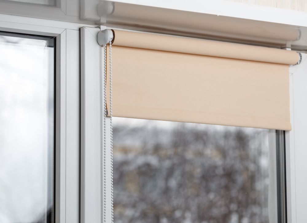 A Beige Roller Blind Partially Covering a White Window — LeSands Screens & Blinds Moss Vale Pty Ltd in Moss Vale, NSW