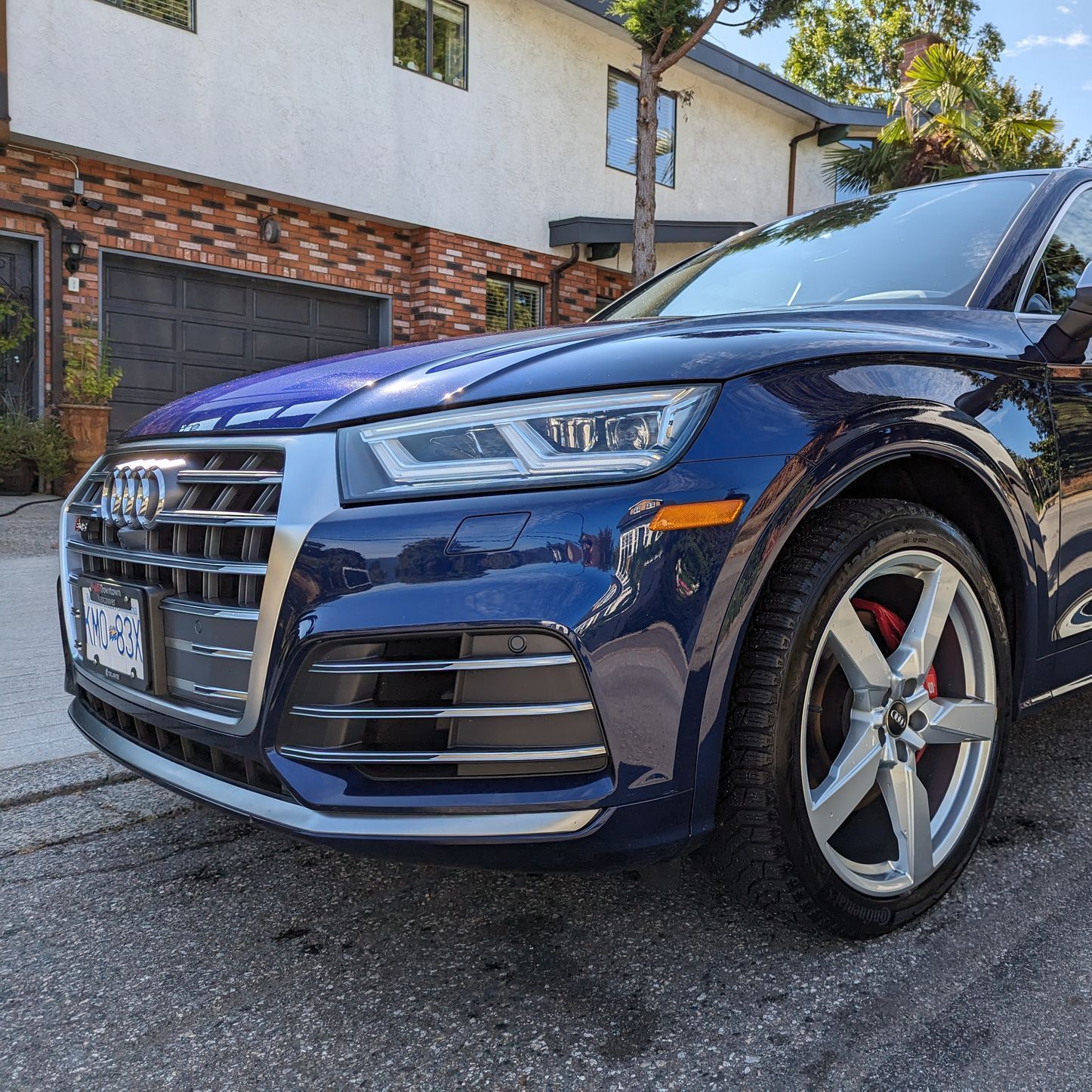 a blue audi q5 is parked in front of a brick house .