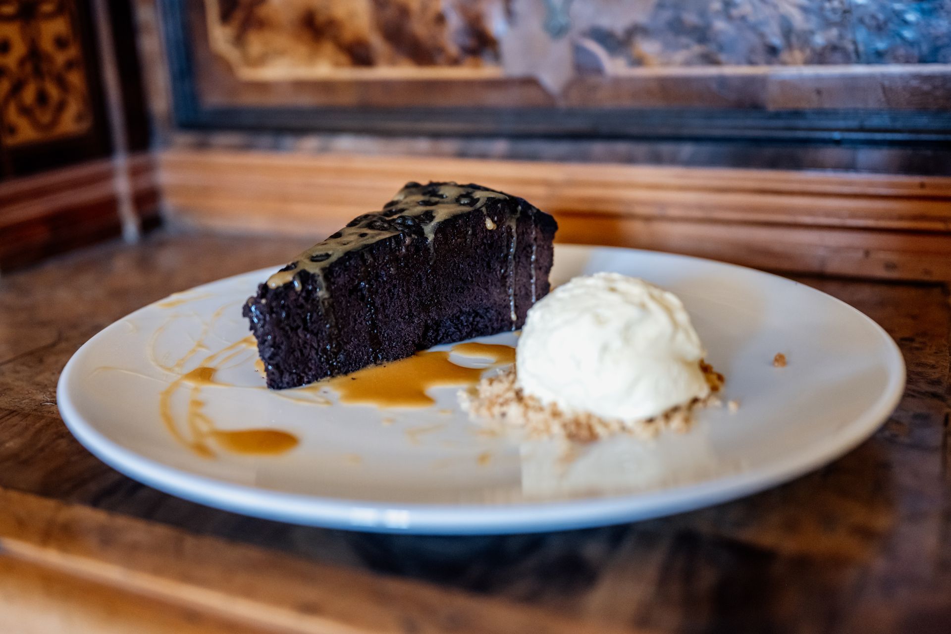 Un piatto bianco sormontato da una fetta di torta al cioccolato e da una pallina di gelato. Osteria dei Frati | Il Cenobio