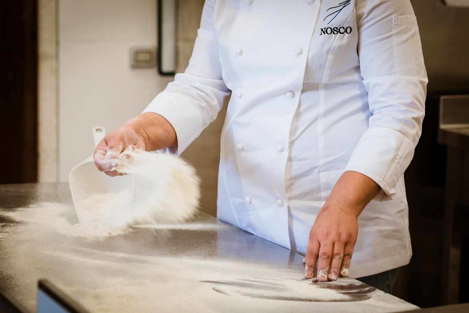 Uno chef versa la farina in una ciotola sul bancone.