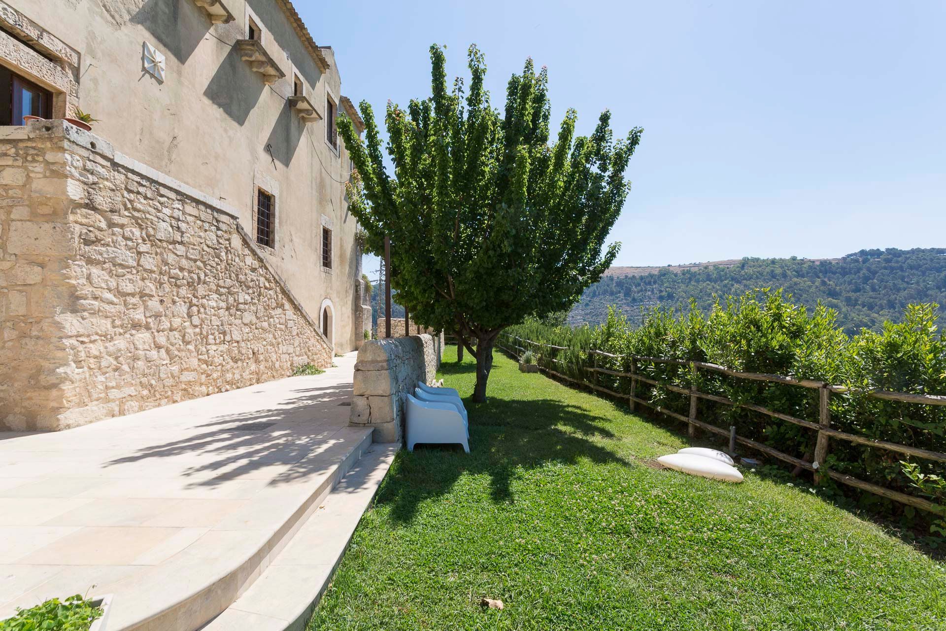 Un grande edificio in pietra con un rigoglioso prato verde davanti | Antico Convento dei Cappuccini | Ragusa Ibla | Sicilia