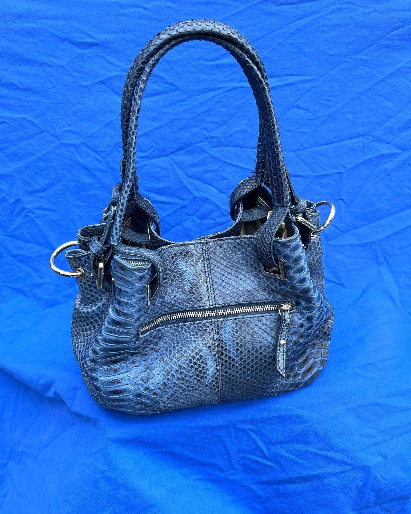 Una borsa di pelle di serpente è appoggiata su un panno blu