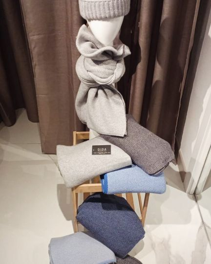 Un manichino che indossa un cappello e una sciarpa è seduto su uno sgabello di legno.