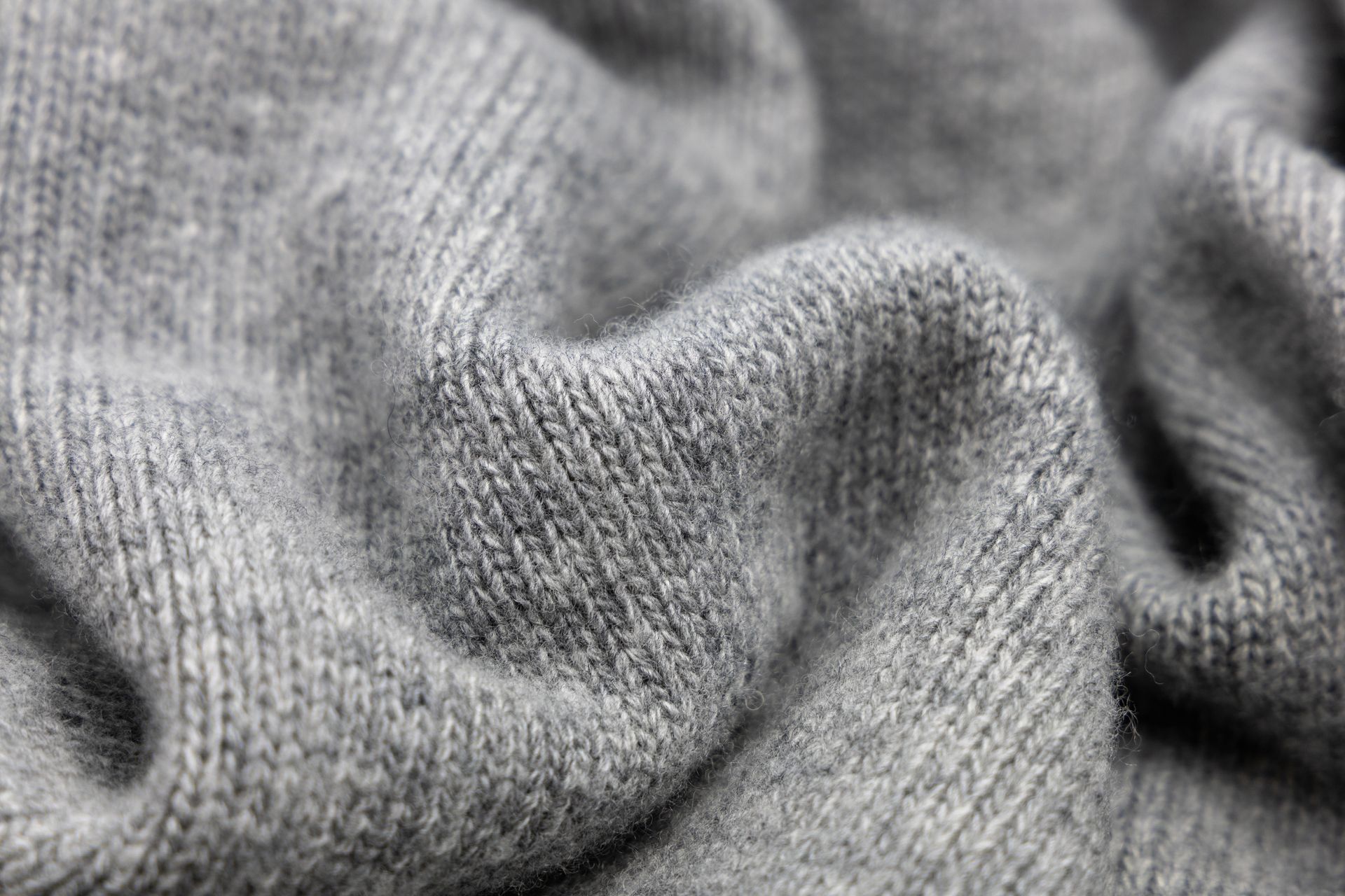 Un primo piano di un maglione grigio mostra la consistenza del tessuto.