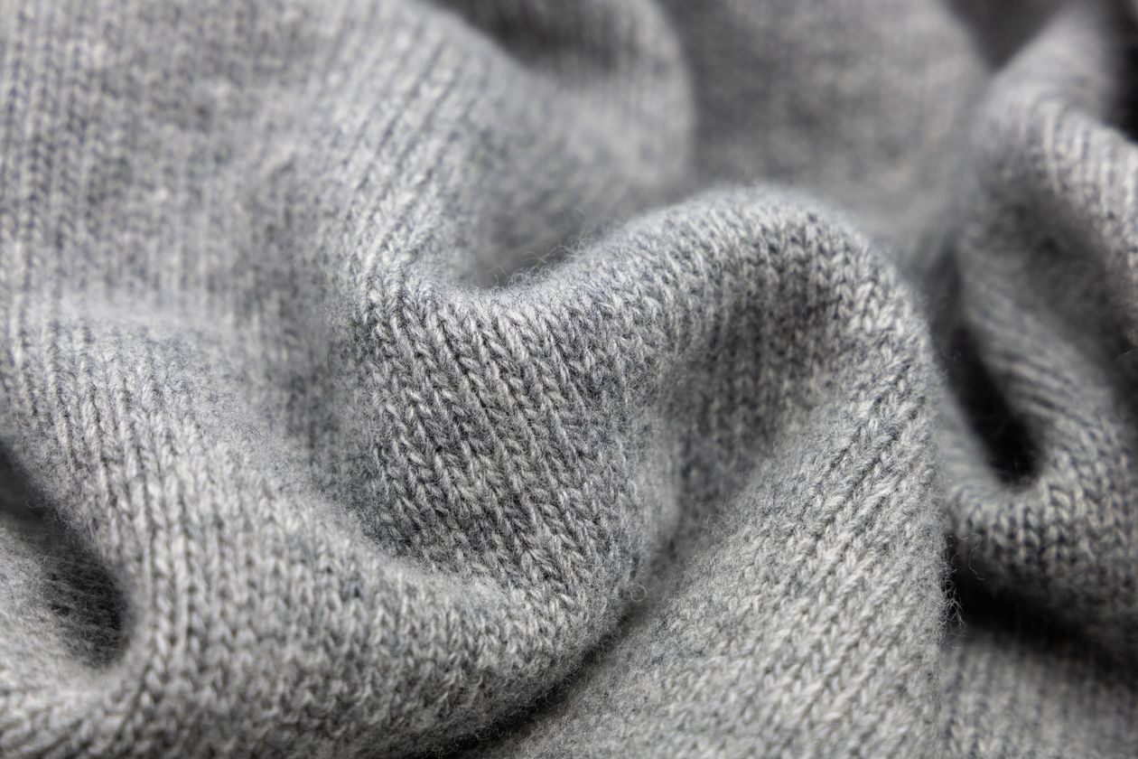 Un primo piano di un maglione grigio mostra la consistenza del tessuto.
