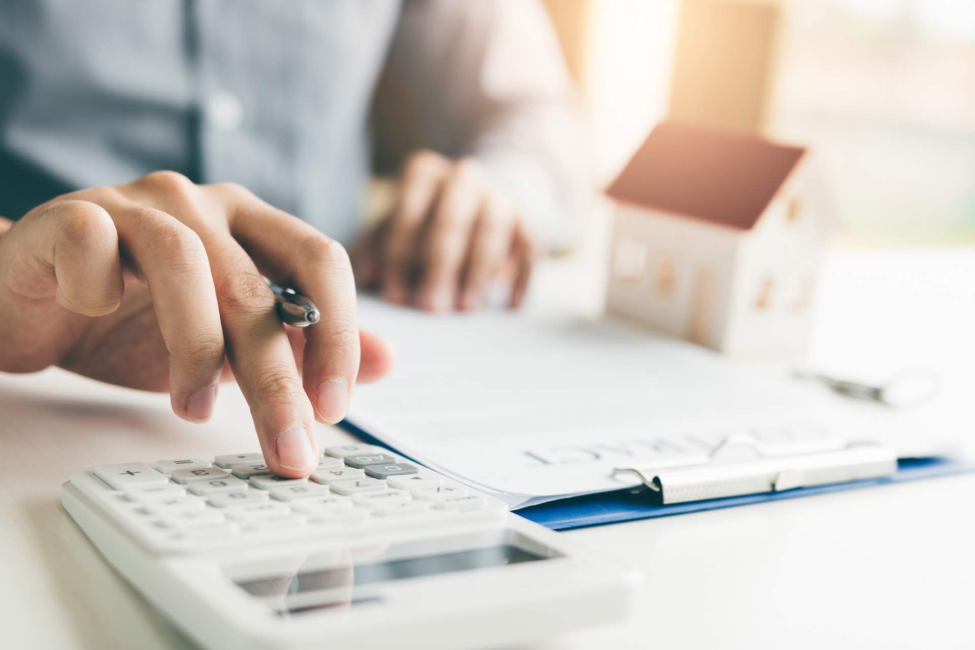 A person is using a calculator to calculate the cost of a house.