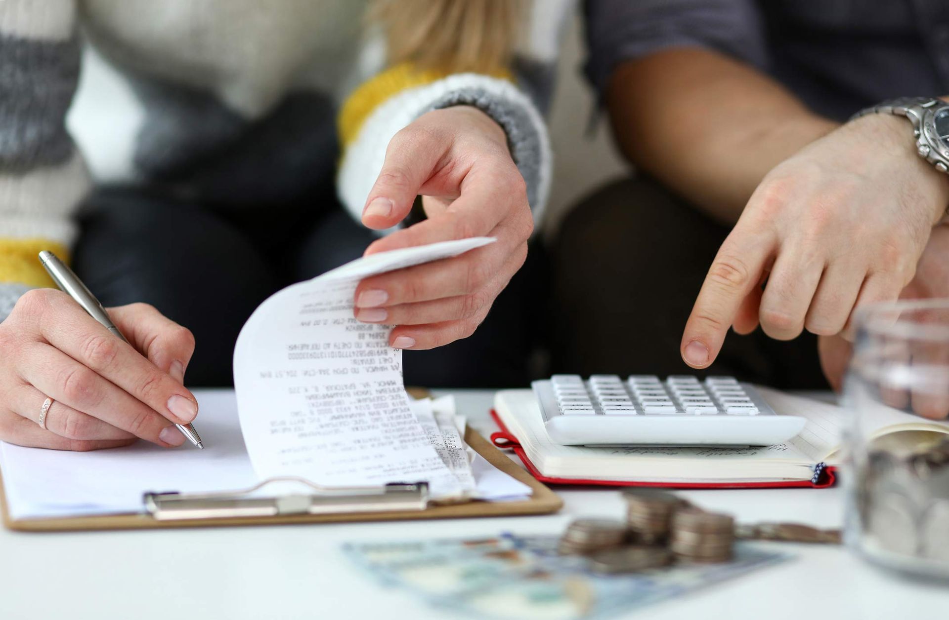 A man and a woman are sitting at a table looking at a receipt and using a calculator.