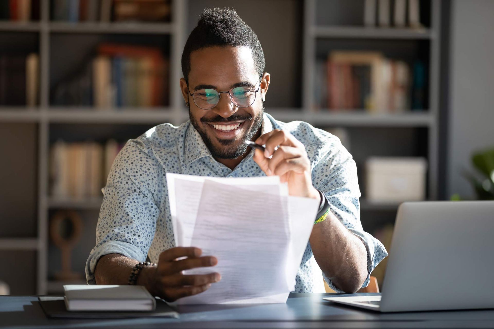 A man is sitting at a desk looking at a piece of paper