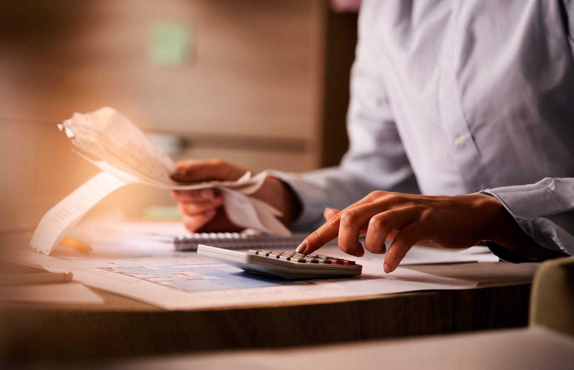 A person is using a calculator while holding a piece of paper.