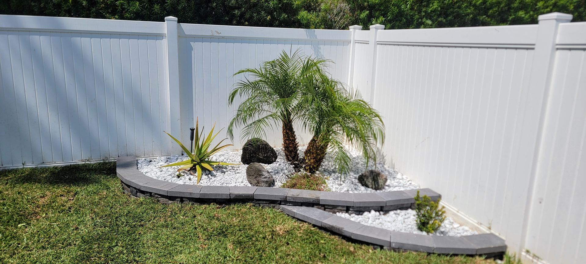 A white fence with a garden in front of it.