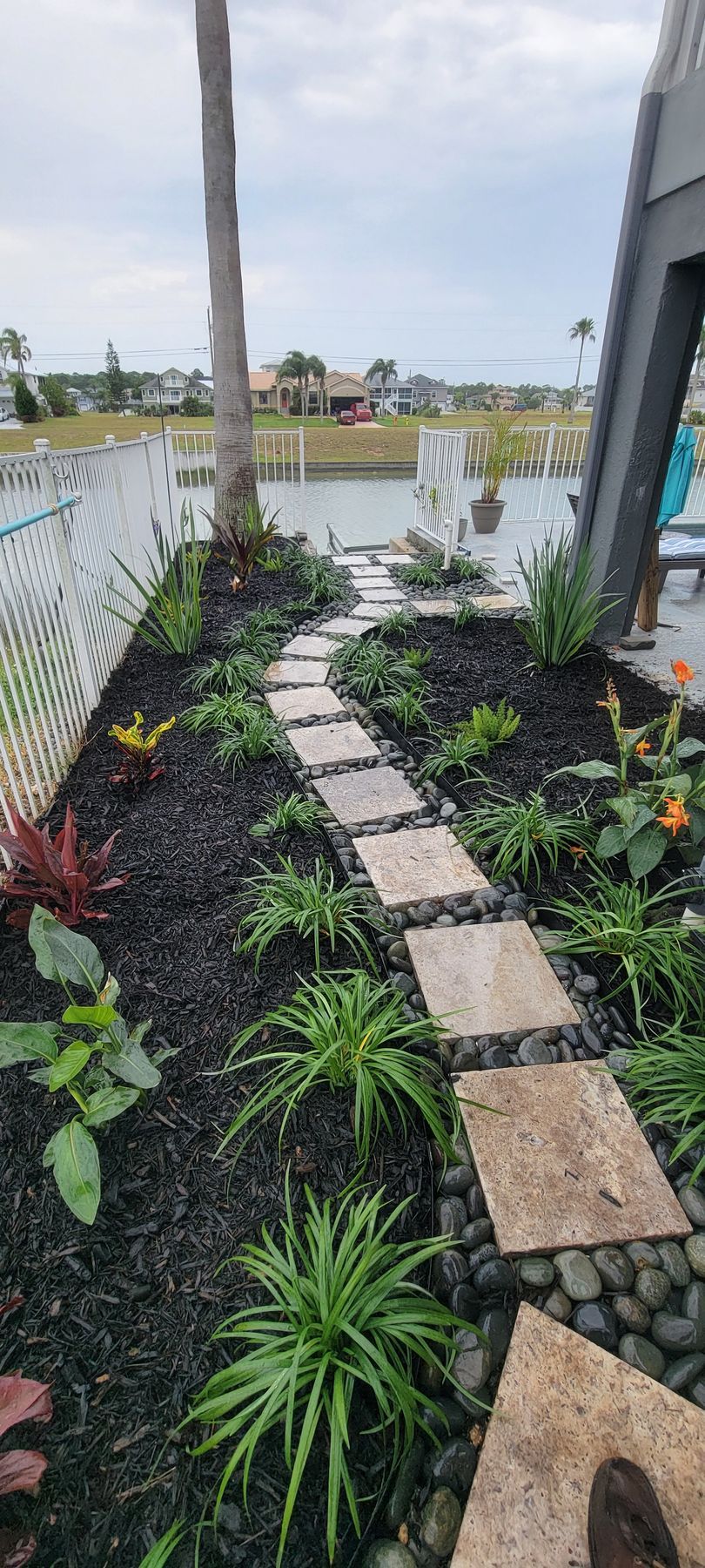 A stone walkway leading to a pond in a garden.