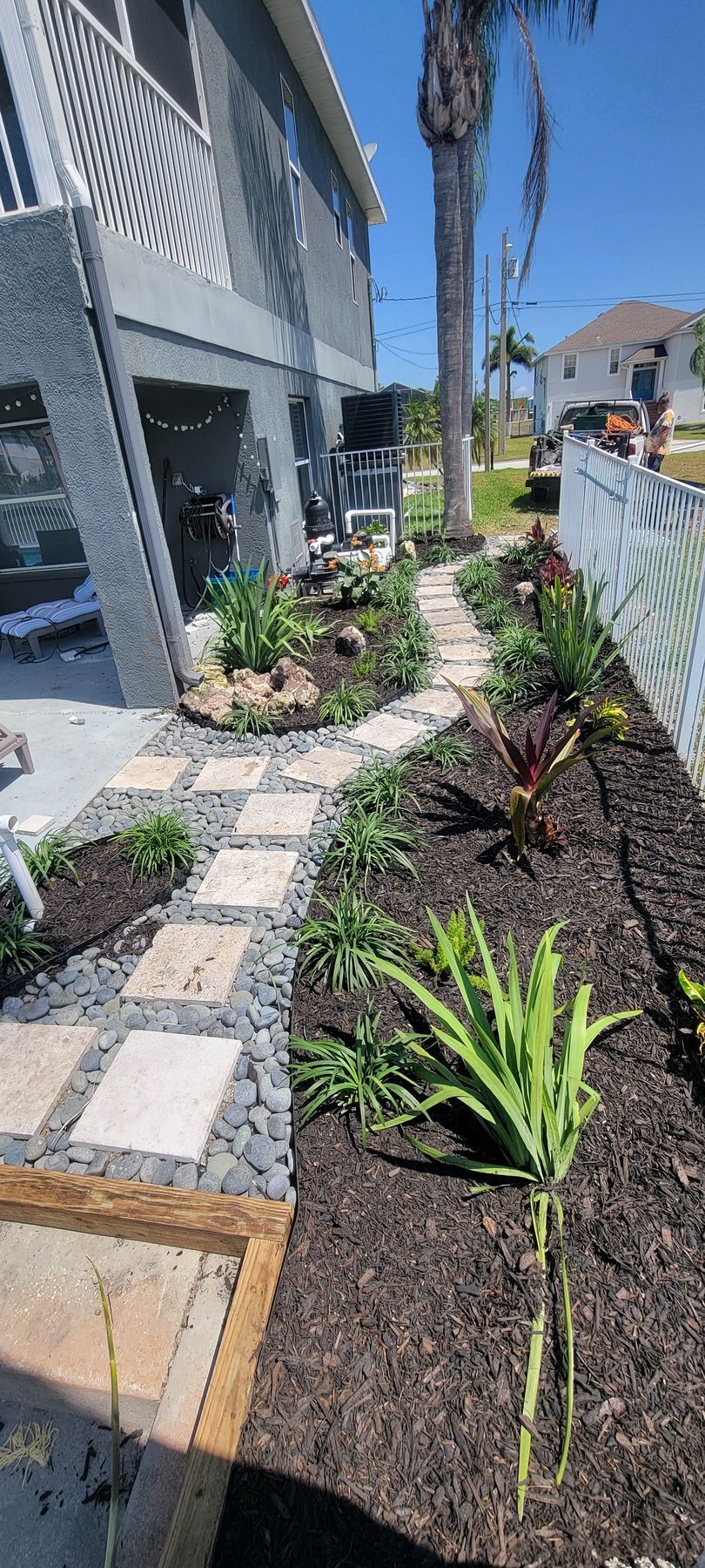 A walkway leading to a house with a palm tree in the background.