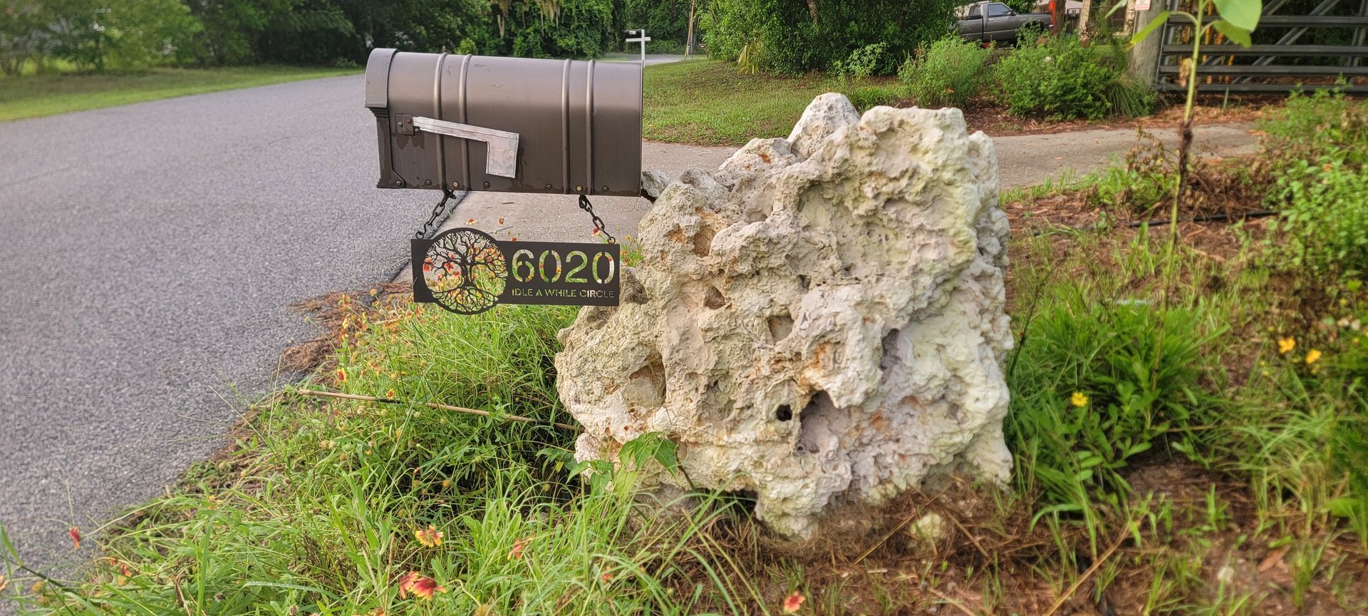 A mailbox is sitting on the side of a road next to a large rock.