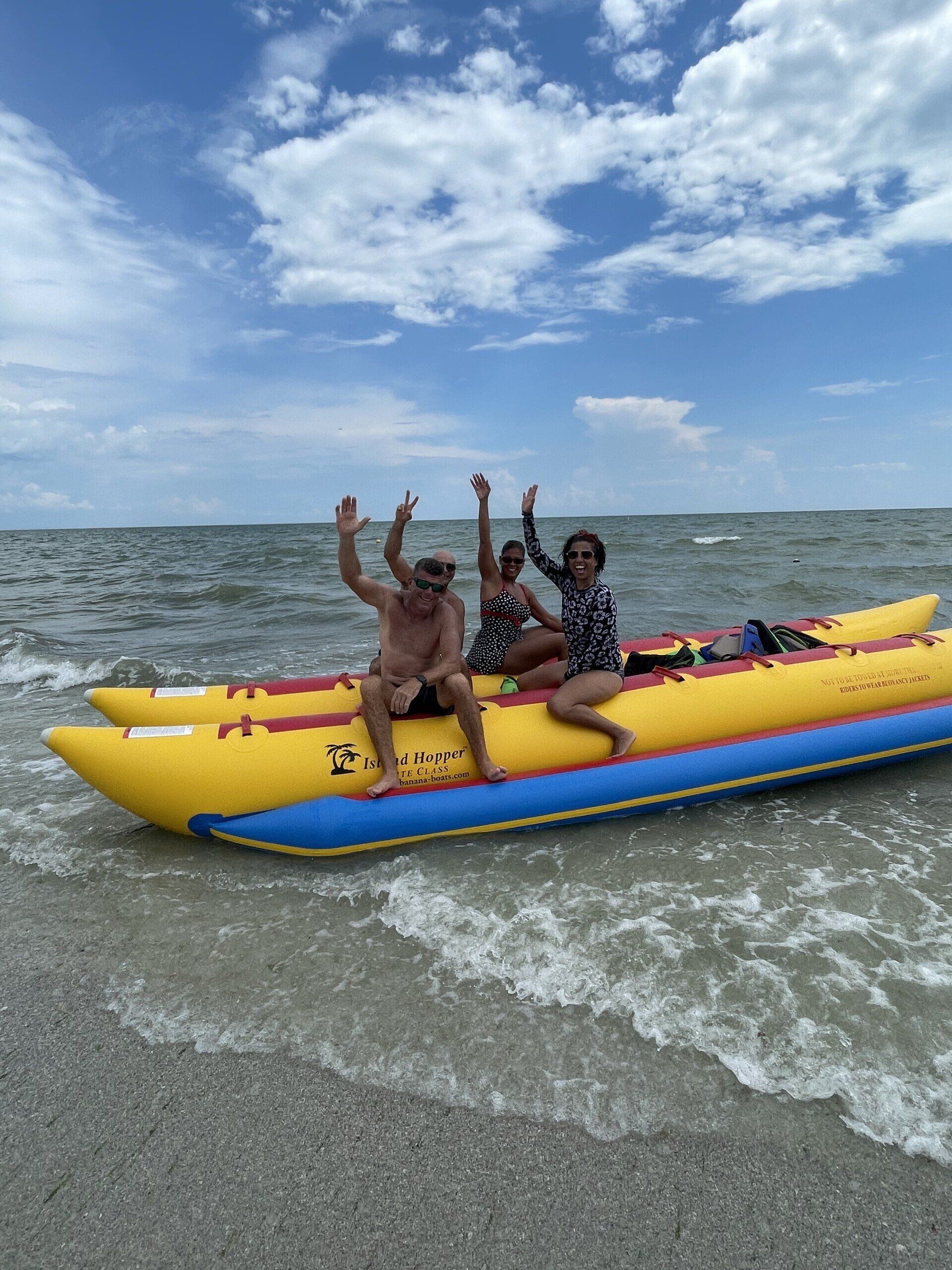 Side view of happy people riding on a banana boat while they hands are in the air
