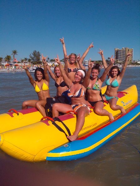 Happy people riding on a banana boat while they hands are in the air