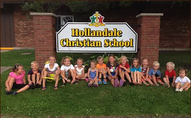 Children seated in front of Hollandale Christian School sign.