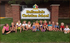 A group of children sit in front of a hollandale christian school sign