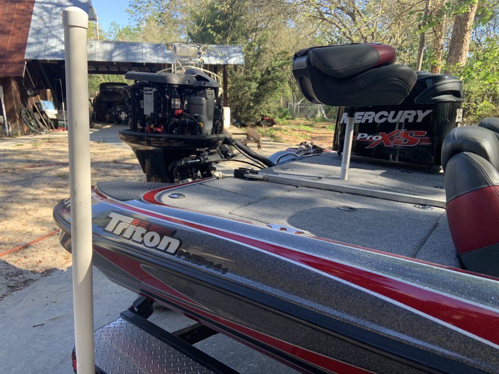 Bass boat with a Mercury Pro XS outboard motor, Triton logo, and black and red accents.