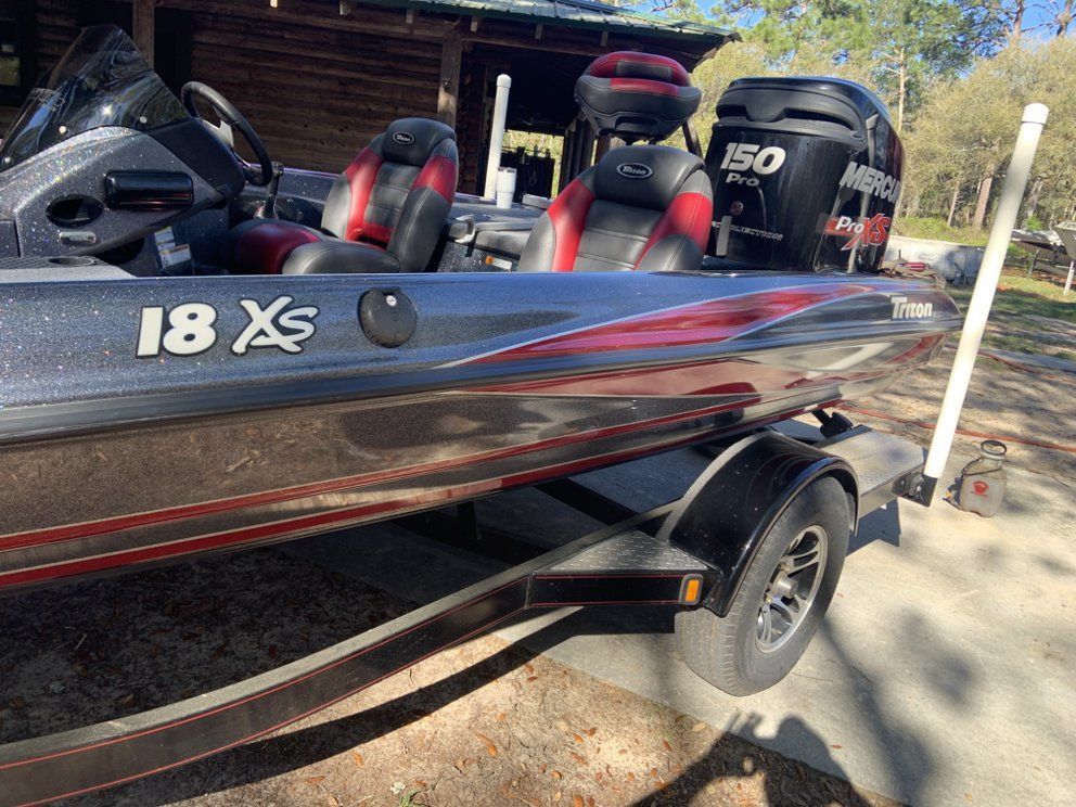 Bass boat on a trailer, black and silver with red accents, 150 hp motor.