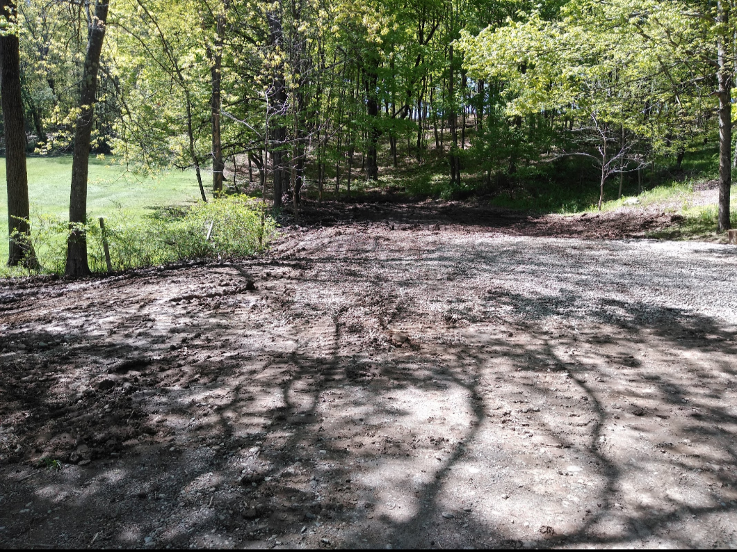 Gravel driveway leading into a wooded area on a sunny day. Tree shadows on the ground. Gravel driveway leading into a wooded area on a sunny day. Tree shadows on the ground.