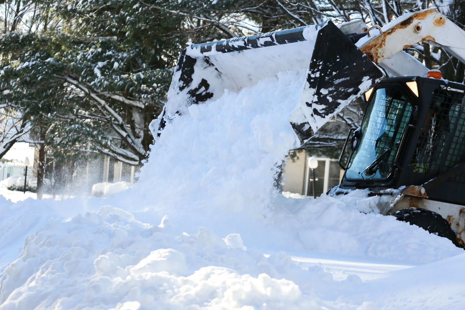 Yellow dump truck hauling snow on a snowy road, trees and blue sky background. Yellow dump truck hauling snow on a snowy road, trees and blue sky background.