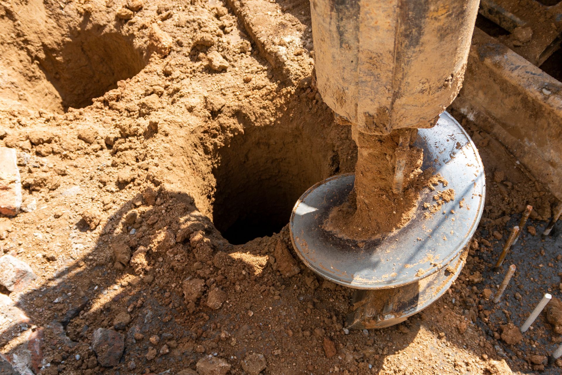 Person using a post hole digger in red soil. Person using a post hole digger in red soil.