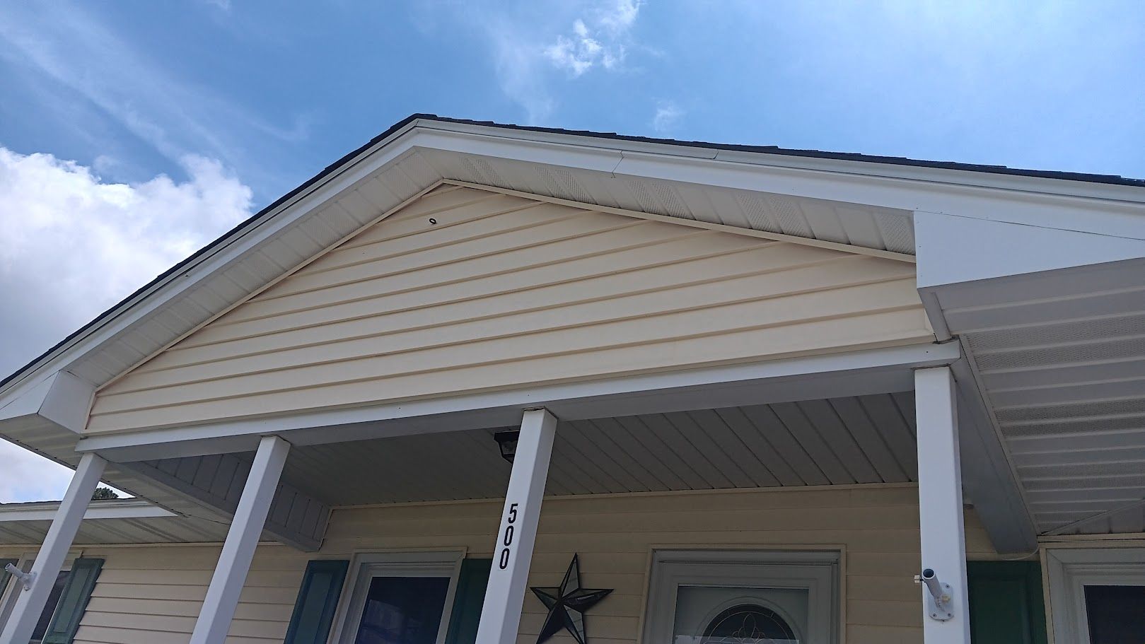 A man is cleaning the roof of a house with a high pressure washer.