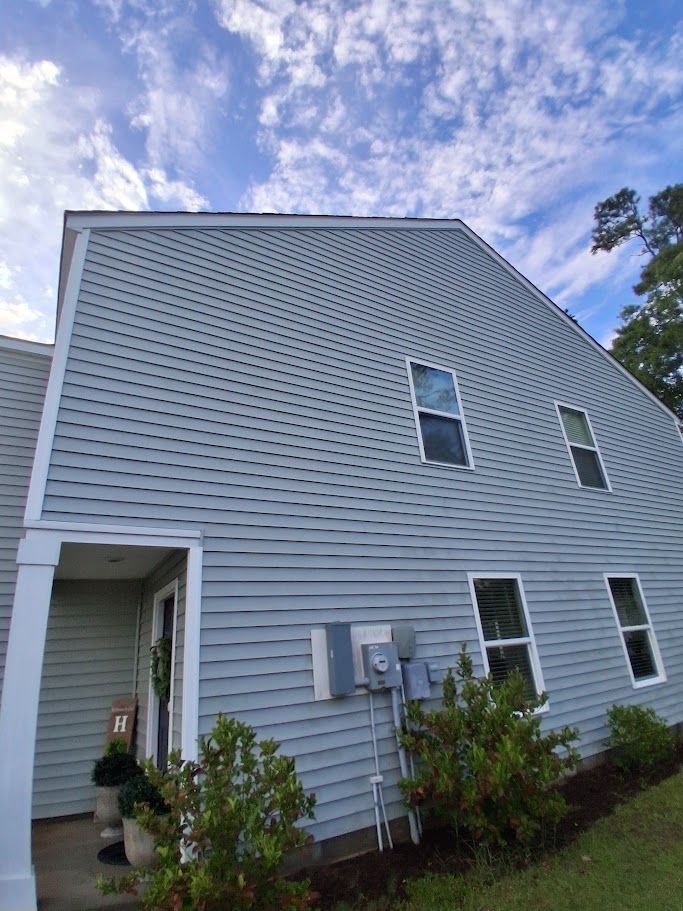 A person is using a pressure washer to clean the side of a house.