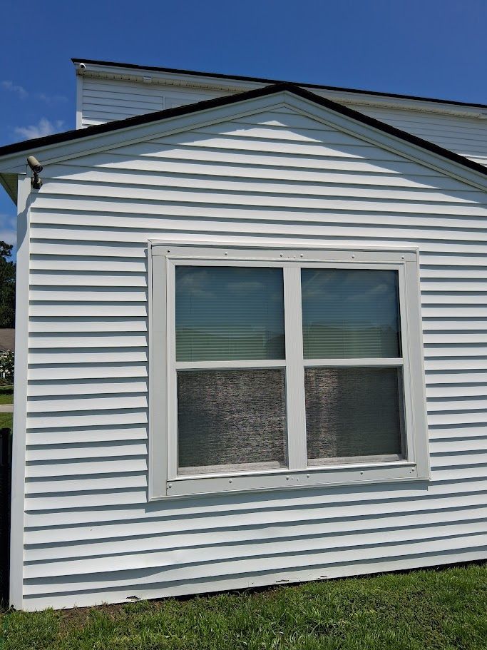 A person is using a high pressure washer to clean the side of a house.