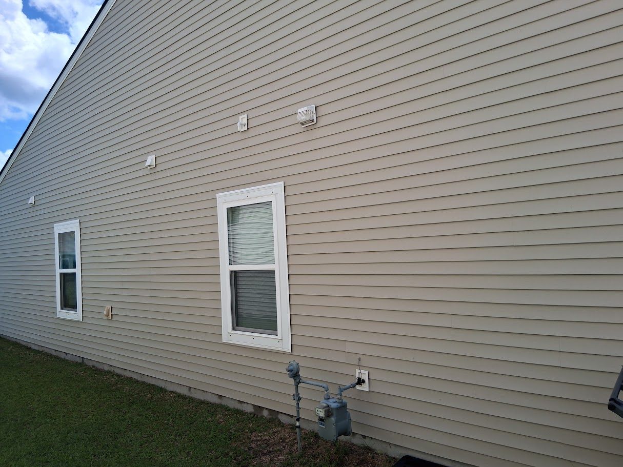 A man is cleaning a carport with a high pressure washer.