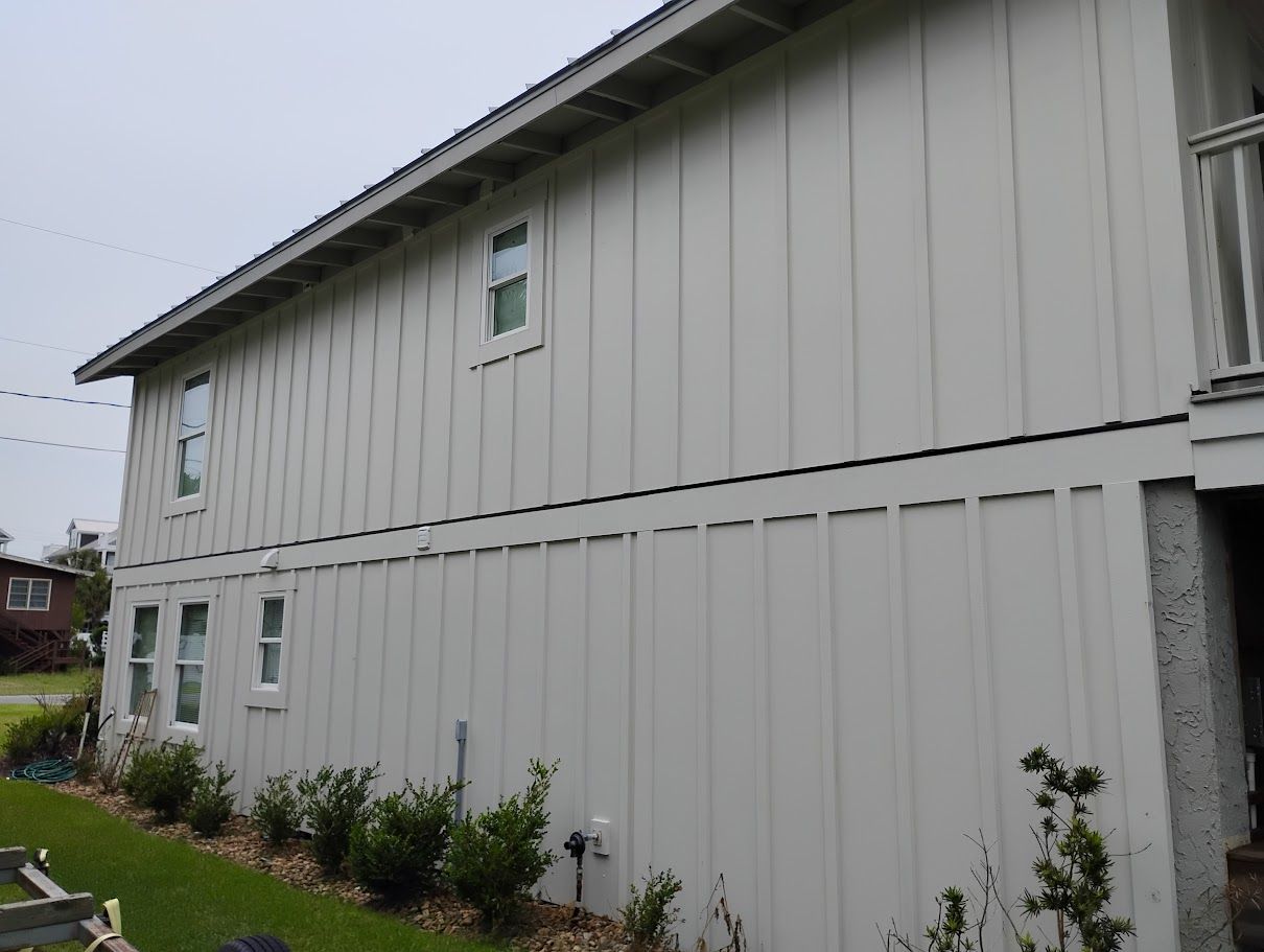 A man is holding a high pressure washer in his hand in front of a house.