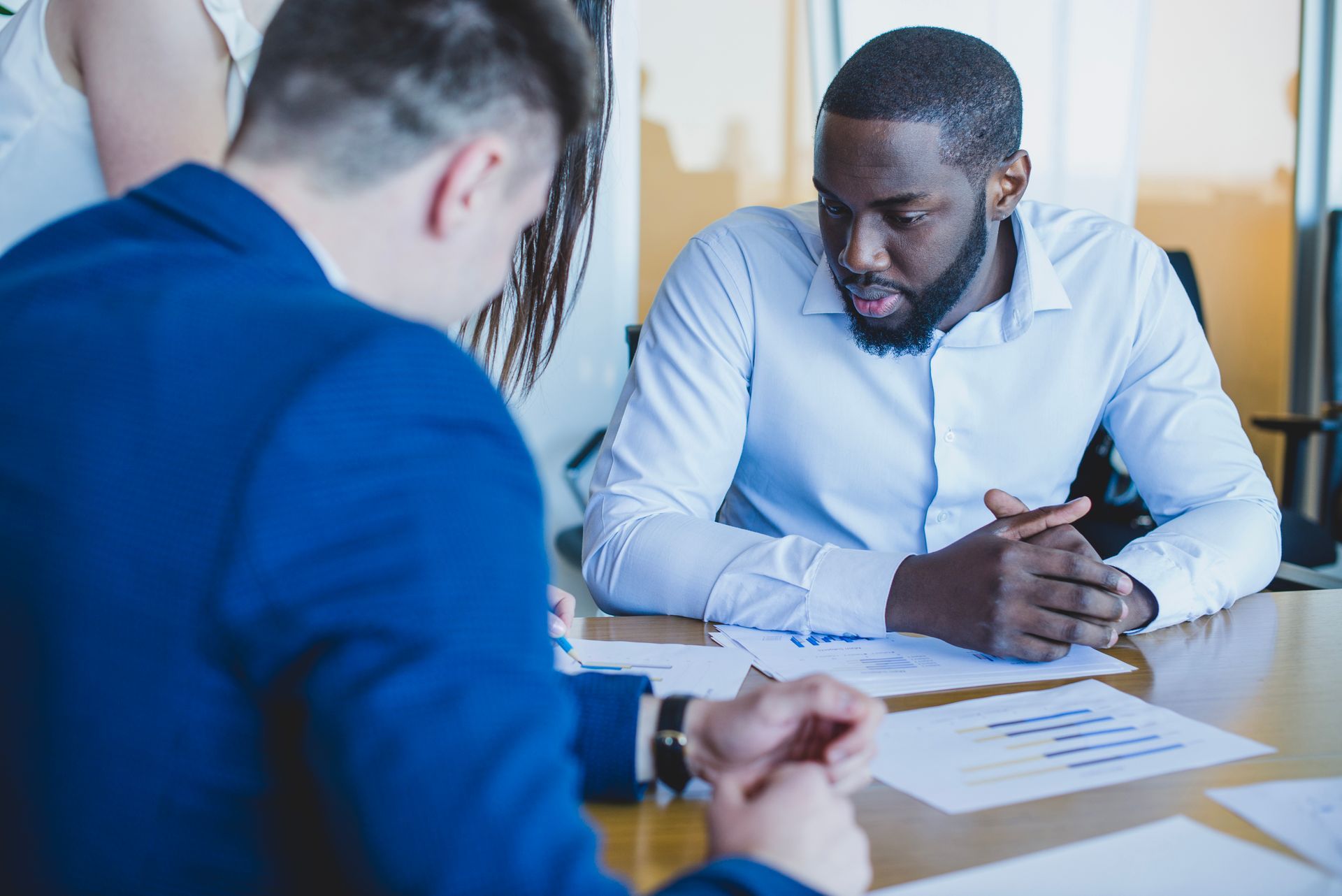 Two men are sitting at a table talking to each other.