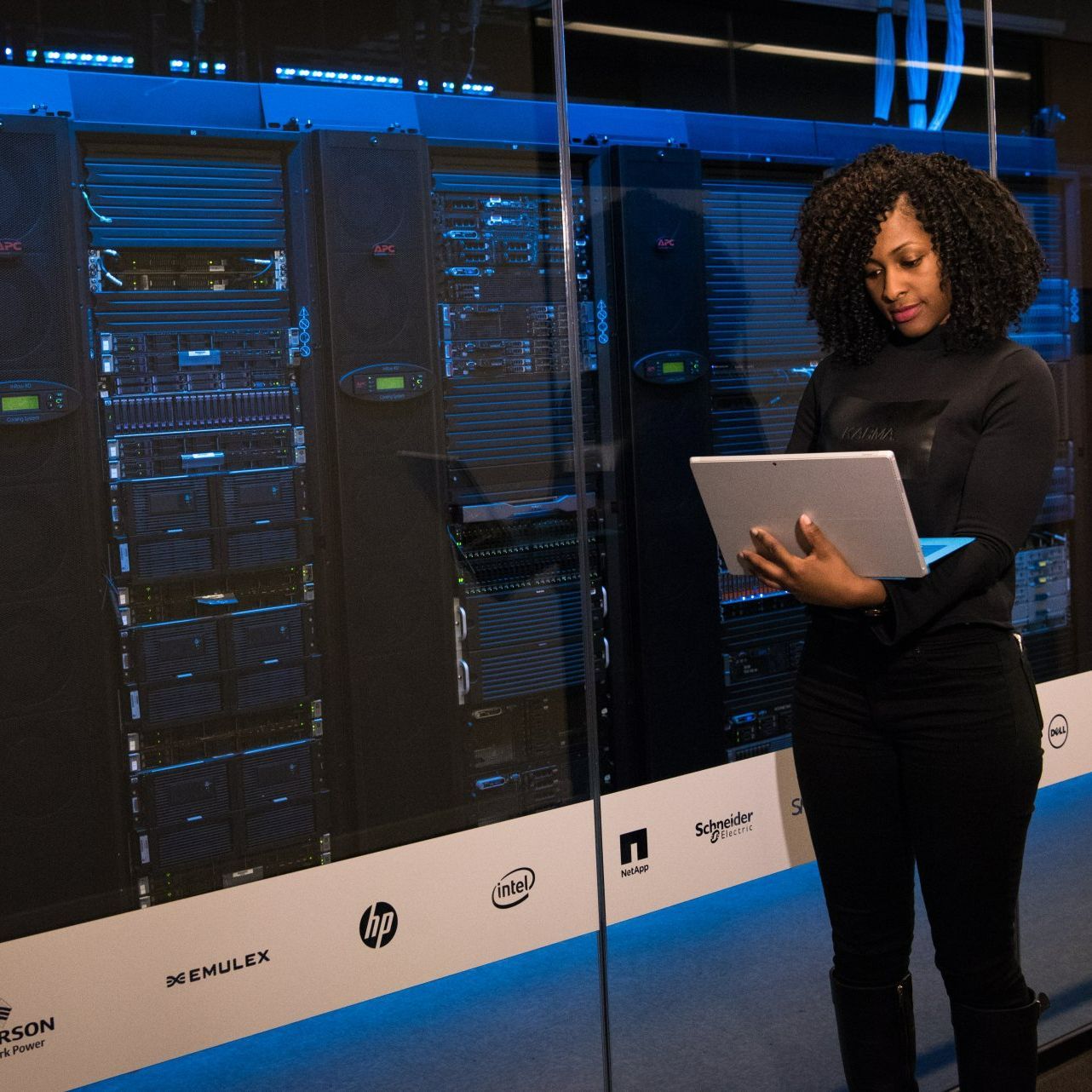 a woman is looking at a laptop in a server room