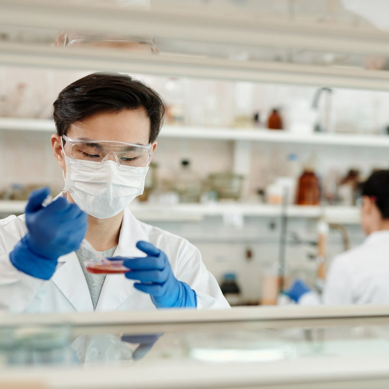 a man wearing a mask and blue gloves is working in a lab