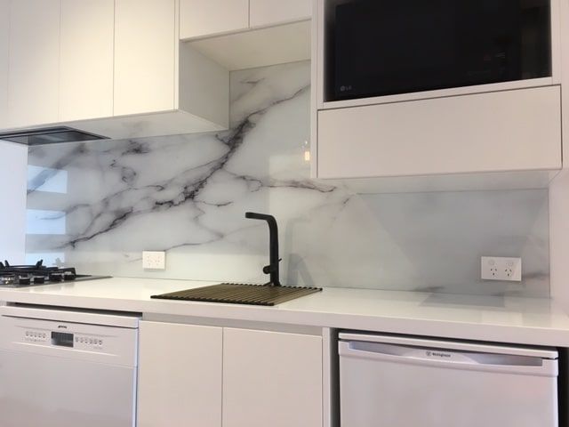A Kitchen with White Cabinets and A Marble Backsplash — DecoGlaze in Cardiff, NSW