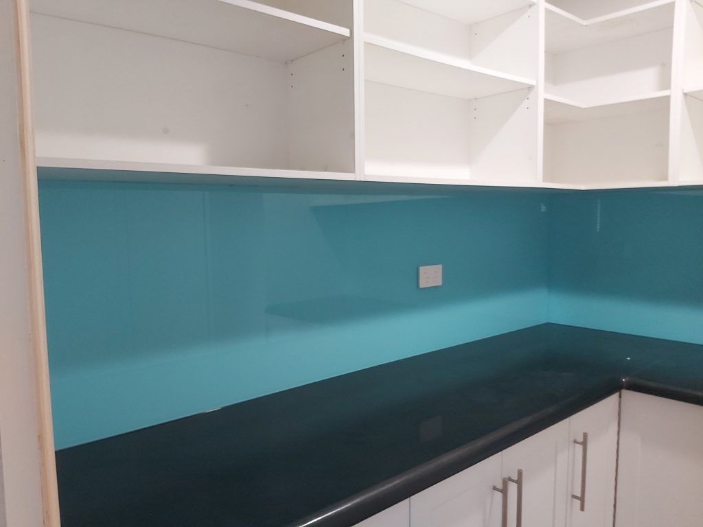 A Kitchen with A Blue Backsplash and White Cabinets — DecoGlaze in Cardiff, NSW