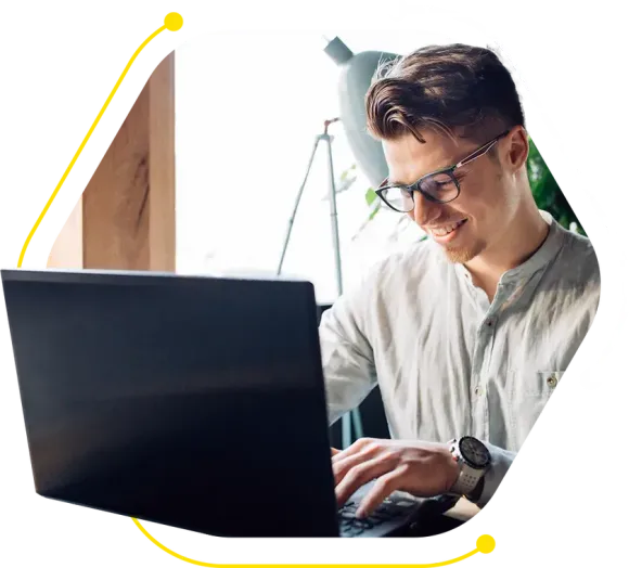 a man wearing glasses is typing on a laptop