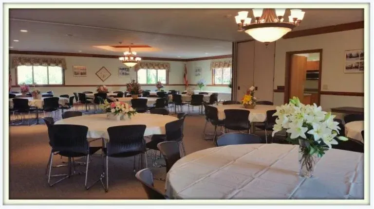 A large room with tables and chairs and a vase of flowers