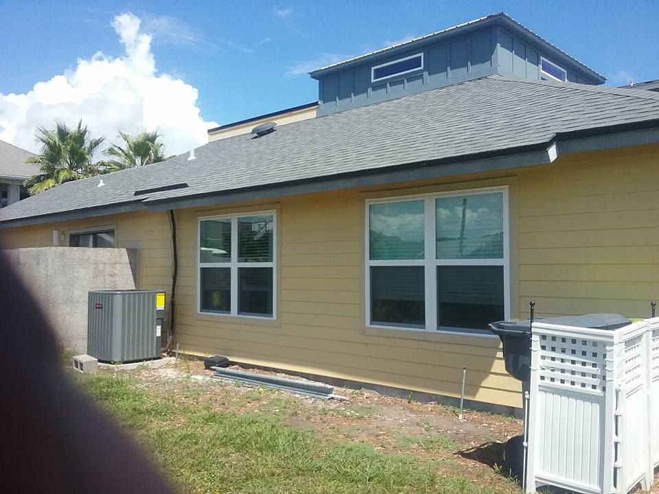 Yellow house with gray roof, white-framed windows, and a blue upper structure.