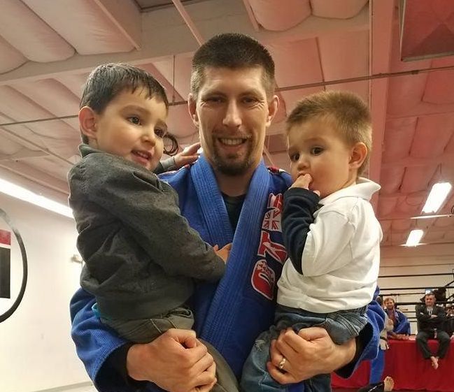 A man in a blue kimono is holding two young boys